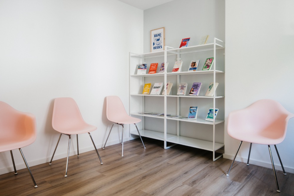 Wartezimmer mit rosa Stühlen und Bücherregal